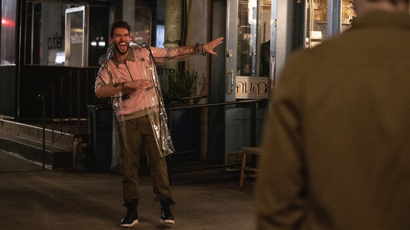 Lance from “The Other Two” wearing a plastic raincoat and dabbing.