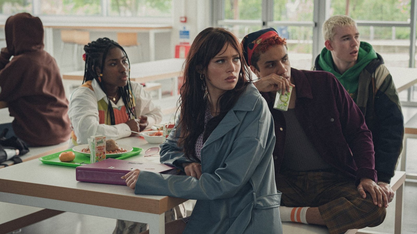 A group of teens sit in a school cafeteria.