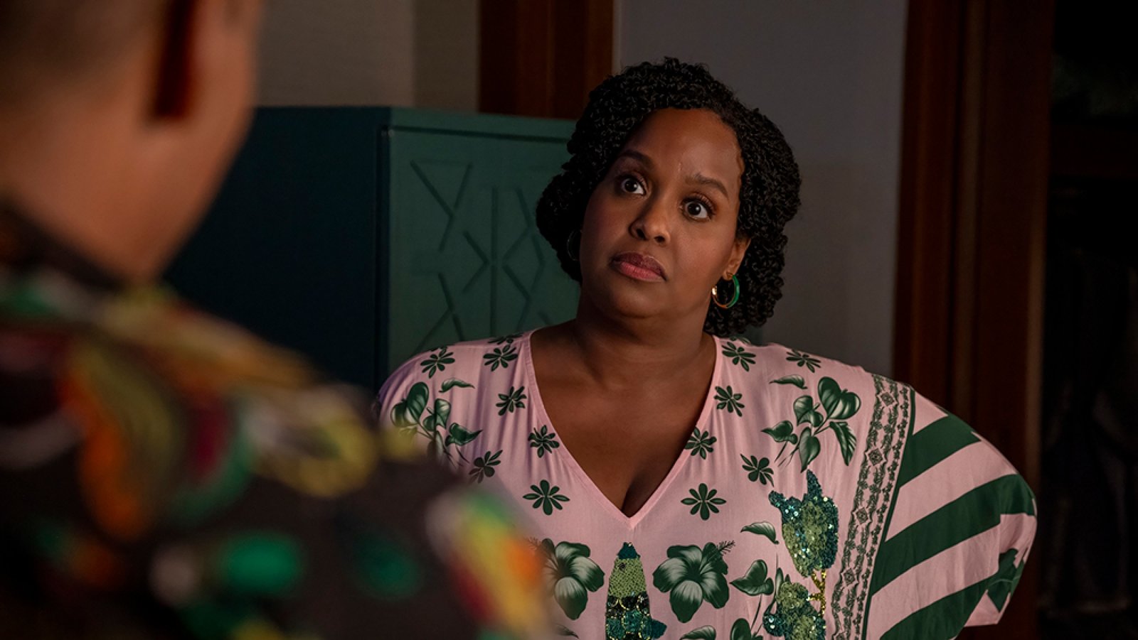 A woman stands opposite a man, looking nervous.