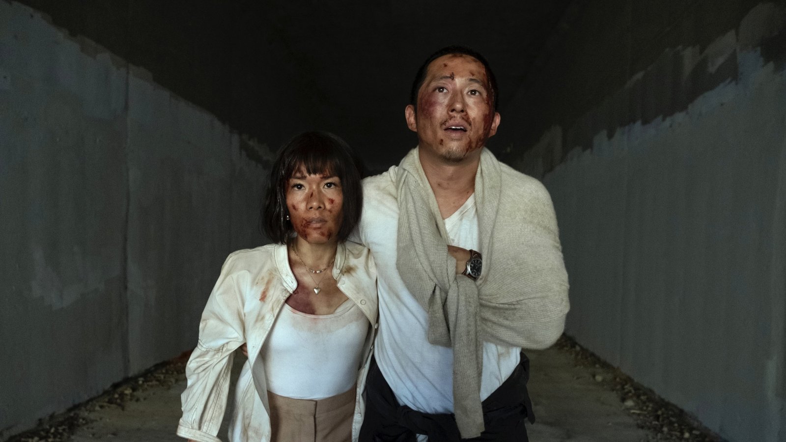 images-13-fill_-size_2000x1125-v1685719199 A man and woman with bloodied faces stumble out of a tunnel holding each other.