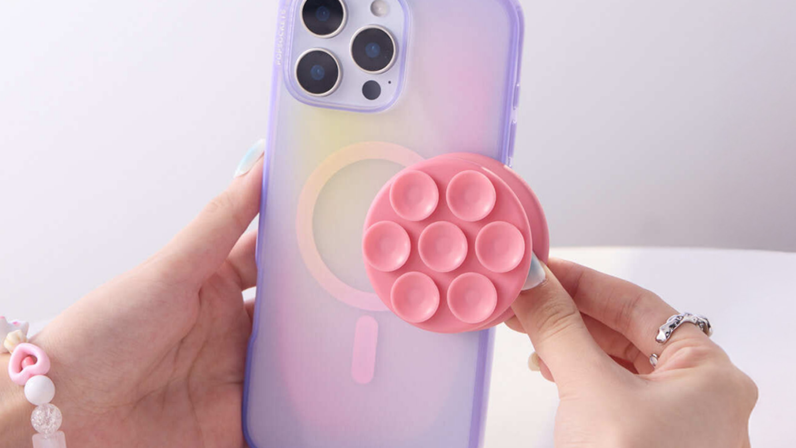 images-2-fill_-size_2000x1125-v1753459845 A person placing a Suck-Up Grip on the back of a phone.