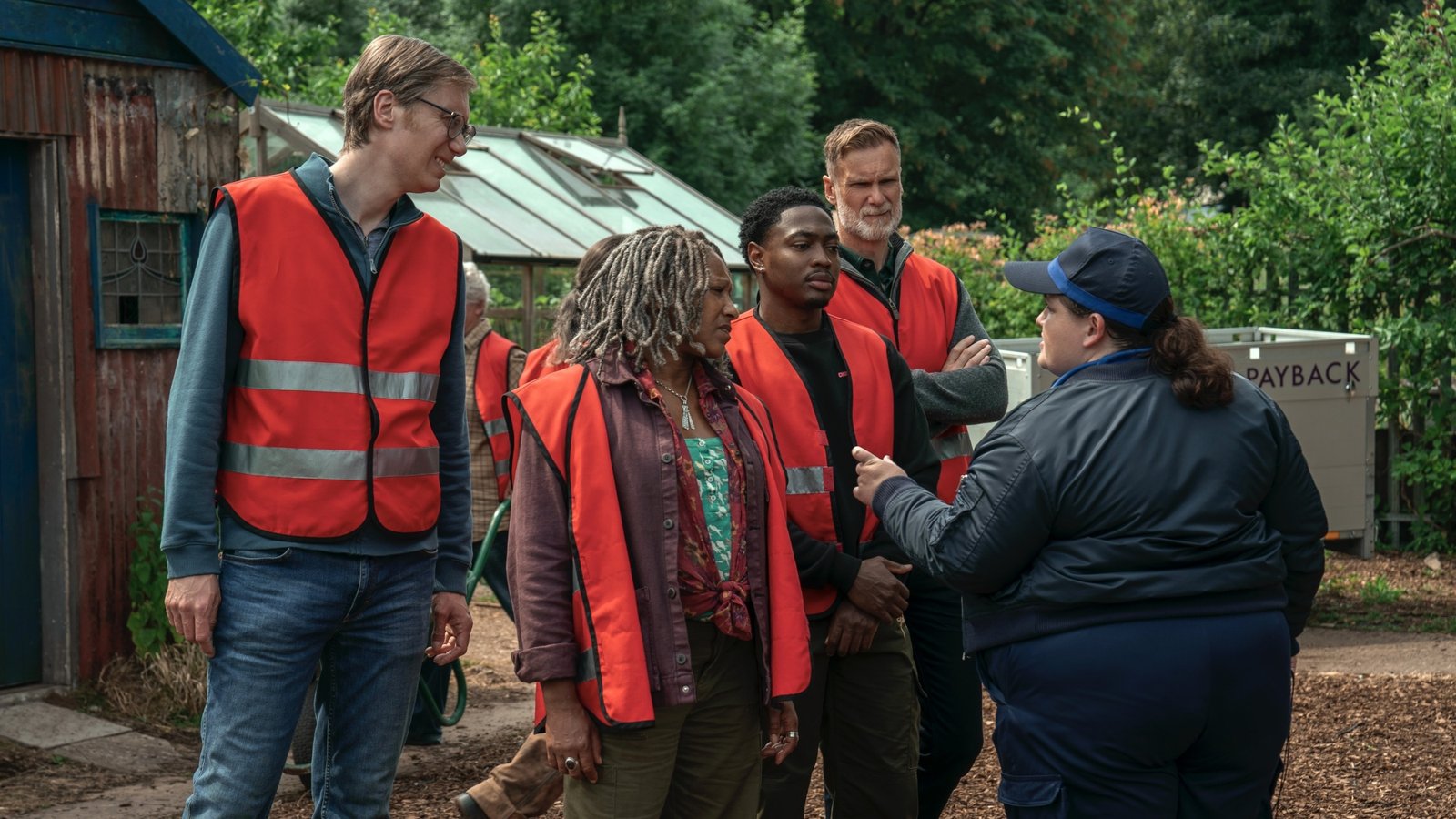 images-3-fill_-size_2000x1125-v1713984808 A group of men and women in red vests outside a community garden.