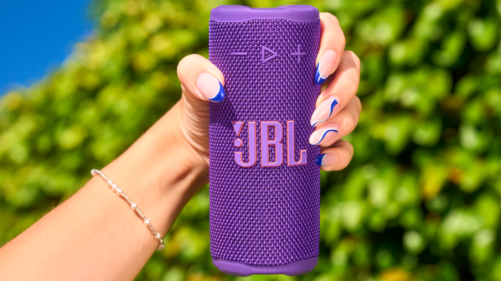 woman's hand holding purple JBL Grip speaker
