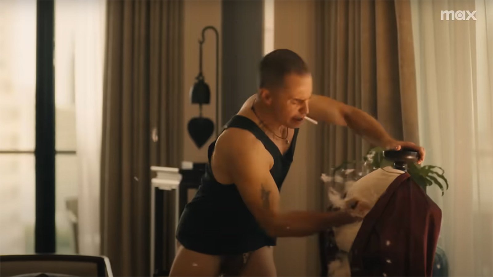 A man in a hotel room stabs something while feathers