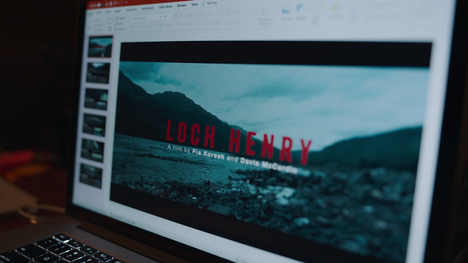 images-4-fill_-size_2000x1125-v1687540427 An open laptop shows the documentary "Loch Henry" with an image of a rocky shore and mountains in Scotland.